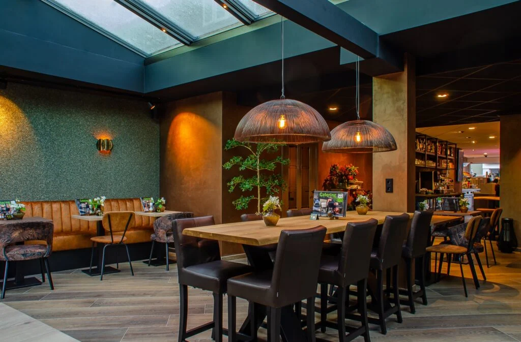 Tafels onder de koperen hanglampen in de verbouwde brasserie