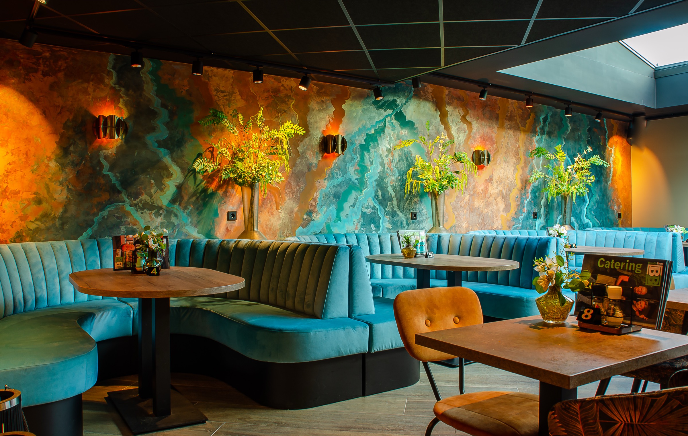 De beschilderde muur met de blauwe banken in de brasserie